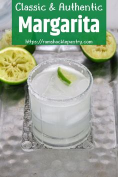 a glass filled with ice and limes on top of a tray next to sliced kiwi