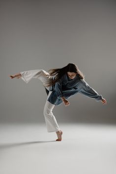 a woman in white pants is doing a trick on a skateboard with long hair