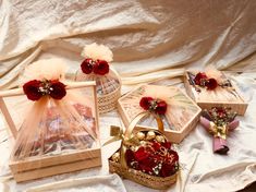 four small boxes with red flowers in them on a white cloth covered surface, one is open and the other two are closed