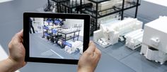 a person is holding up a tablet with an image of a factory on the screen