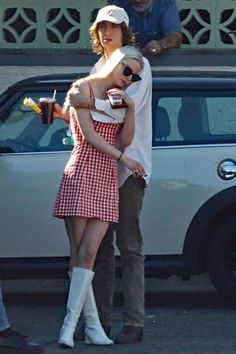 two people standing next to each other in front of a white car with their arms around one another