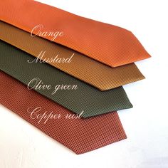 four different colors of ties are stacked on top of each other with the words orange, mustard, olive green and copper next to them