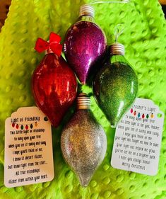 four christmas ornaments are sitting on a green blanket with some cards attached to the ornament