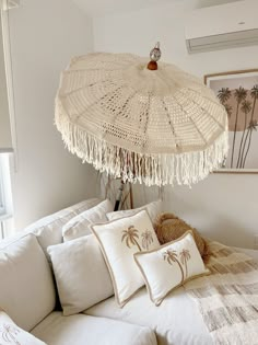 a white couch with pillows and an umbrella hanging from it's ceiling in a living room