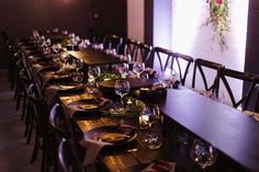 a long table is set up with place settings for dinner and wine glasses on it