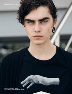 a young man with dark hair and piercings wearing a black t - shirt