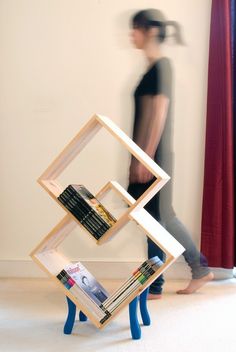 a person walking past a book shelf with magazines on it and a man in the background