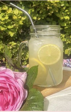 a glass jar filled with lemonade next to a pink rose