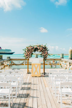 an outdoor ceremony setup with white chairs and flowers on the altar, overlooking the ocean