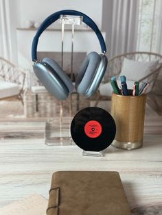 an old record, headphones and pen holder are sitting on the table next to a notepad