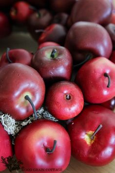 a pile of red apples sitting on top of a wooden table