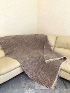 a couch with a blanket on top of it next to a white wall and floor