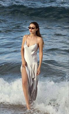 a woman in a white dress standing on the beach