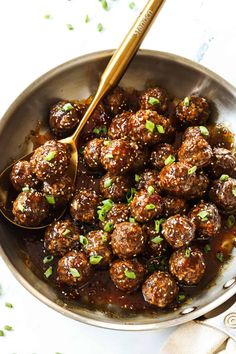 meatballs are being cooked in a pan with a spoon and garnished with parsley