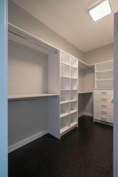 an empty closet with white shelving and black carpeted flooring is seen in this image