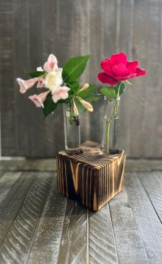 two vases with flowers in them sitting on a wooden table next to each other