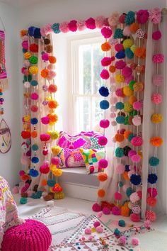 a bedroom decorated in bright colors with pom - poms hanging from the window