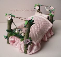 there is a pink bed made out of branches with flowers and pearls on the top