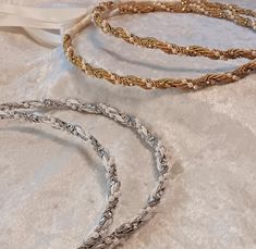 two gold and silver bracelets sitting on top of a white cloth covered tablecloth