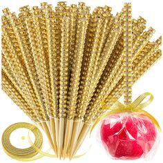 a bunch of straws and an apple in a bag next to some gold string