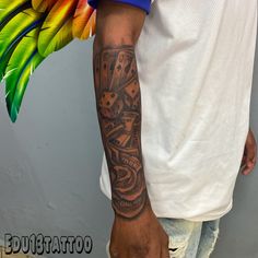 a man with a tattoo on his arm holding a colorful bird wing in front of him