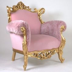 a fancy pink chair with gold trimmings on the arm and back, sitting in front of a white background