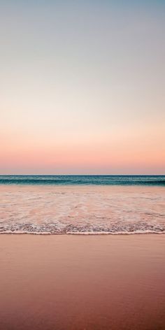 two people walking on the beach at sunset