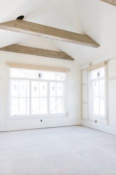 an empty room with white walls and wood beams