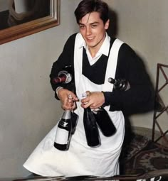 a man in an apron holding two bottles of wine