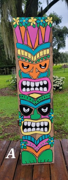 a wooden board with an image of a tiki mask painted on it