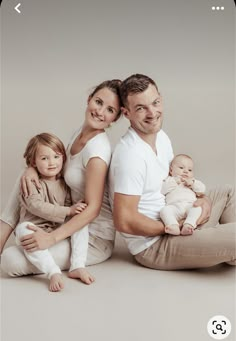 a man, woman and child are sitting on the floor with their arms around each other