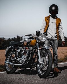 a man standing next to his motorcycle on the road