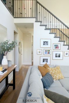 a living room filled with furniture and pictures on the wall next to a stair case