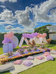 an outdoor party setup with balloons and pillows on the grass in front of a building