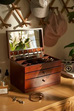 an open jewelry box sitting on top of a wooden table next to a mirror and other items