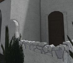 a white stucco building with a brown door and window on the outside wall, surrounded by plants