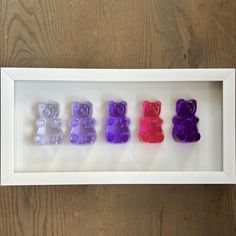 four small bears in a white frame on a wooden table