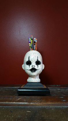 a white skull with pencils sticking out of it's head on top of a wooden table