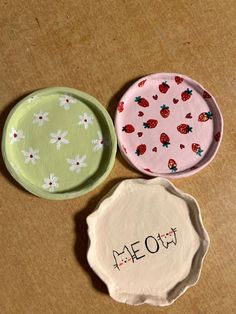 three small plates with designs on them sitting on a table next to the word meow