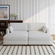 a white couch sitting on top of a black and white rug