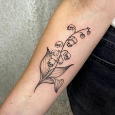 a woman's arm with a lily of the valley tattoo on her left forearm