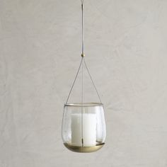 a candle is hanging from a wire with a glass container filled with white candles on it