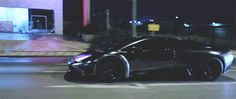 a black sports car driving down a street at night