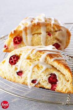 two pastries with icing and raspberries sit on a cooling rack