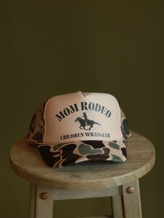 MOM RODEO 🤠 CHILDREN WRANGLER For the moms with wild ones! Our Mom Rodeo hat is available in two different colors.     DETAILS- Hand printed and hand pressed 100% Polyester Front 100% Polyester Mesh Back OSFM Made to order     Mom hat. Western hat. Rodeo hat. Women's hat. Trucker hat Rodeo Hat, Rodeo Mom, Camo Trucker Hat, Hat Bar, Mom Hat, Custom Trucker Hats, Western Hat, Mom Hats, Western Hats