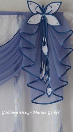 the curtains are hanging on the wall with blue ribbons attached to them and some white buttons