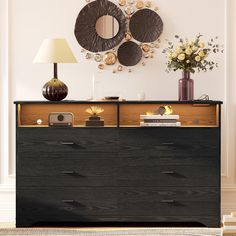 a black dresser with two mirrors above it and flowers on the top shelf next to it