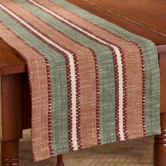 a wooden table topped with a green and red striped table runner on top of a wooden table