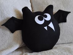 a black bat stuffed animal laying on top of a bed