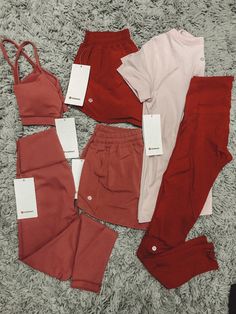 four pieces of red and pink clothing are on the floor with tags attached to them